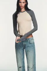 Camiseta de manga larga tipo ranglán con cuello redondo. Presenta un diseño bicolor con cuerpo en tono beige y mangas en gris jaspeado, con bajo redondeado.