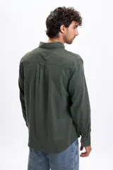 Camisa de manga larga confeccionada en micropana color verde militar, con cuello abotonado, bolsillo frontal y cierre de botones.