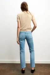 Jeans de mezclilla azul claro, tiro medio, corte recto y ligeramente acampanado en el bajo. Presenta cinco bolsillos y cierre frontal con cremallera y botón metálico.