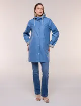 Pilot engomado impermeable color azul, de corte recto estilo trench con acabado resistente al agua. Cuenta con capucha integrada, cierre frontal con broches a presión, bolsillos laterales con ojal y forro interior de tela estampada a cuadros visible en la solapa y los puños.