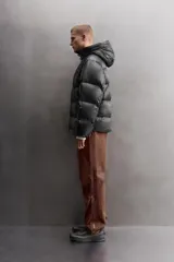 Campera puffer negra con capucha ajustable, cierre frontal con cremallera, bolsillos laterales con cremallera oculta y relleno de plumón y pluma.