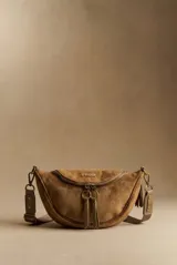 Riñonera de diseño curvo confeccionada en material sintético con acabado tipo gamuza color tostado. Presenta cierre frontal con doble tirador de argollas metálicas, placa metálica con logo de la marca y correa ajustable con herrajes de bronce.