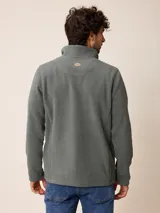 Sweater de polar color beige, con cuello alto y cierre frontal parcial. Presenta un pequeño logo bordado en el pecho.