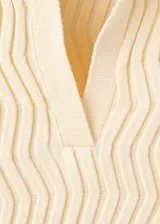 Chaleco de punto fino color amarillo claro, con diseño entallado, cuello polo y manga corta.