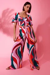 Pantalón ancho estampado de crepe, con pliegues, bolsillos laterales, bragueta con cremallera y forro interior, con diseño de ondas en tonos rosa, rojo, verde y naranja.