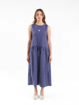 Vestido largo sin mangas, de calce amplio y relajado, con falda fruncida y escote redondo. Presenta diseño a rayas, detalles de bordado a contratono en las sisas, logo frontal y botones en la espalda.