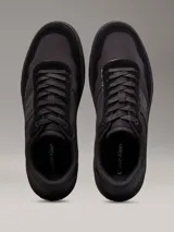 Zapatillas urbanas Calvin Klein de color negro, con detalles en cuero y gamuza. Presentan el logo de la marca en el lateral y suela de goma.
