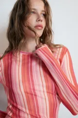 Remera de punto fino de manga larga y cuello redondo, con diseño de rayas verticales en tonos rosados, rojos y naranjas.