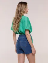 Short de denim blanco tiro alto, estilo pull-on con cintura elástica ancha, bolsillos delanteros y traseros, y dobladillo en las piernas.