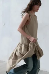 Vestido midi sin mangas de cuello redondo, con falda amplia con frunces y bolsillos laterales ocultos. Presenta cierre en la espalda con abertura y botón.