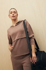 Canguro color beige de la línea Essence, con capucha, corte amplio y detalle de recorte frontal.