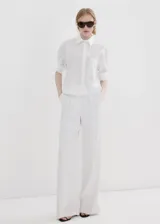 Camisa blanca de corte recto con mezcla de algodón y lyocell, adorno de perlas, cuello camisero, manga larga con puños abotonados y cierre delantero con botones ocultos.