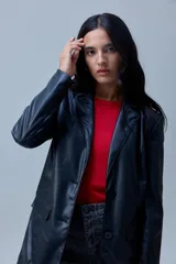Blazer de eco cuero negro con cuello de solapa, cierre frontal con botones y bolsillos aplicados en la parte delantera. Cuenta con forro interno a tono.