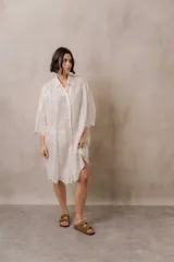 Camisola blanca de silueta amplia y caída liviana, con bordados florales sutiles, cuello camisero, cierre frontal de botones y mangas 3/4.