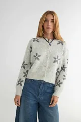 Cardigan de punto con estampado de flores, cuello redondo y cierre frontal con botones. Presenta un diseño de corte holgado con puños y ruedo acanalados.