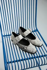 Chatas de cuero con estampado de piel de serpiente en tonos blanco y gris, con punta cuadrada, tira sobre el empeine y hebilla metálica.