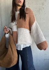 Sweater de punto con diseño de bloques de color en tonos camel y crudo, de corte holgado, cuello redondo y mangas largas con puños anchos.