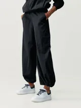 Pantalón estilo paracaídas color verde claro, de tejido técnico Wind_S, con bolsillos laterales y reguladores en la cinturilla y en el bajo.