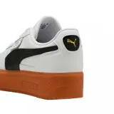 Championes urbanos Puma modelo Palermo Platform, color negro con franja lateral blanca y suela de plataforma color caramelo. Presenta detalles en dorado en la lengüeta y el lateral.