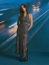 Vestido largo negro con escote drapeado tipo halter y falda transparente.