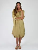 Camisola larga de lino color amarillo verdoso, con cuello camisero, cierre frontal de botones y mangas largas con presilla para arremangar.