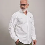 Camisa blanca de algodón Oxford, de manga larga, con cuello abotonado y logo bordado en el pecho. Diseño exclusivo de Ganbaru Collection, hecha en Uruguay.