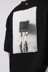 Remera negra de corte oversize con cuello redondo y estampa frontal pequeña con el texto 90's en color blanco.