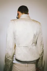 Chaqueta corta de estilo militar con cuello alto y manga larga. Confeccionada en tejido jacquard con diseño floral, presenta botones metálicos en relieve en el cierre frontal, hombros y puños. Incluye trabillas en los hombros, forro interior y acabados desflecados.