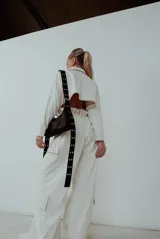 Bolso negro con correa larga regulable con hebillas plateadas.