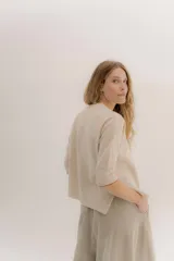 Buzo básico de lambswool color gris oscuro, con escote en V y mangas 3/4. Presenta un fit amplio y tajos laterales. Los puños tienen un detalle de ribete en color celeste y amarillo.