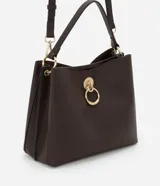 Bolso mediano color marrón oscuro, con doble asa corta y correa larga extraíble. Presenta textura símil cuero y detalle de aro dorado en el frente.