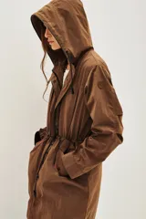 Trench color marrón con capucha, cierre frontal, cordón ajustable en la cintura y bolsillos laterales. Incluye un chaleco interior con estampado animal print.