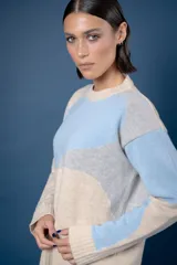 Buzo de punto con diseño abstracto que simula un paisaje, cuello redondo y mangas largas. Confeccionado en lana, presenta una combinación de colores en tonos beige, celeste y gris.