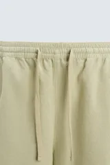 Bermuda de algodón color blanco, de corte relajado (relaxed fit), con cintura elástica ajustable mediante cordón. Posee bolsillos laterales y un bolsillo trasero de plastrón. Presenta un bordado en contraste en la pernera.