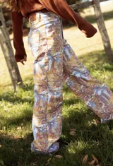 Pantalón tipo jean de corte recto con estampa exclusiva de diseño artístico en tonos tierra, ocres y azules. Presenta bolsillos traseros y cierre con botón metálico.