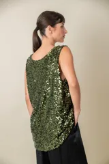 Blusa sin mangas confeccionada en tela cubierta de lentejuelas doradas y plateadas, con escote redondo y corte holgado.