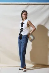 Top blanco sin mangas con textura y lazos negros en el frente.