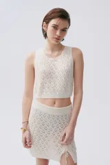 Falda corta de tejido calado color crudo con cintura elastizada y cordones laterales.