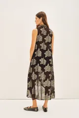 Camisa larga sin mangas, abierta al frente con cuello mao, confeccionada en tejido negro transparente con estampado floral en hilo dorado metalizado.