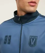 Saco deportivo celeste confeccionado en helanca, con cuello alto, cierre por cremallera, manga larga, estampa lettering y detalles contrastantes.