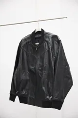 Campera tipo bomber de cuero ovino color marrón oscuro, con cuello de tejido acanalado y cierre frontal con cremallera.