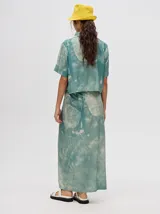 Falda midi tipo pareo color verde con estampado estilo tie-dye en tonos azul, naranja y blanco, con tiras ajustables en la cintura.