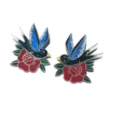 Par de aros con forma de golondrinas sobre una rosa, estilo tatuaje tradicional.