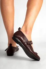 Chatas de cuero color chocolate, con punta redondeada, tira sobre el empeine con hebilla plateada y pequeño moño decorativo en la punta.
