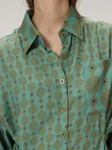 Camisa de algodón con estampado geométrico de ondas en tonos marrón y negro, corte holgado, mangas largas y cuello clásico.