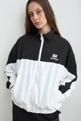Campera estilo aviador de tela avión, en diseño bicolor negro y blanco, con cierre frontal y cuello alto. Cuenta con bolsillos laterales con cierre y bordado de la marca Mandinga en el pecho.