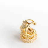 Par de aros ear cuff dorados con cristales claros y diseño de corona. Confeccionados en acero con baño de oro de 18k.