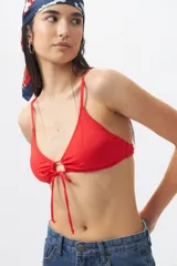 Top de bikini blanco con escote halter, abertura circular en el centro y lazos ajustables.