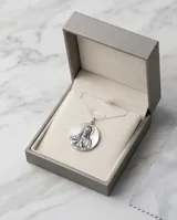Collar triple de plata con cadenas finas de eslabones. El diseño incluye una cadena superior con un pequeño cilindro, una intermedia con una cuenta esférica y una inferior con un dije circular grabado con la imagen del Sagrado Corazón.