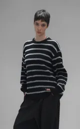 Sweater de cuello redondo con diseño de rayas horizontales en negro y gris. Presenta una textura suave y peluda, con terminaciones en punto rib en el cuello.